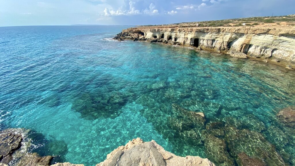 Majestic sea caves of Cape Greco against the backdrop of azure blue waters.