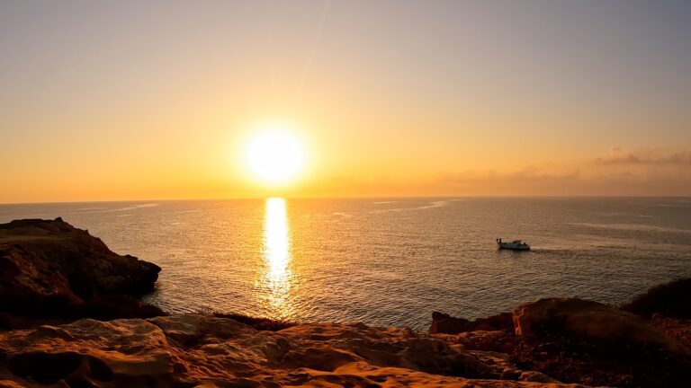 Sunrise over Cape Greco, Cyprus, illuminating a fisher's boat near the shore, capturing the awakening beauty of nature.