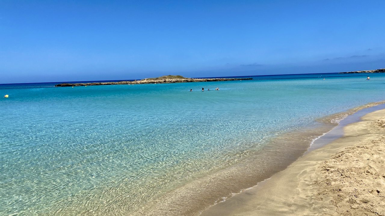 Crystal-clear waters and soft sands of Fig Tree Bay in Protaras, Cyprus, inviting beachgoers for a swim.
