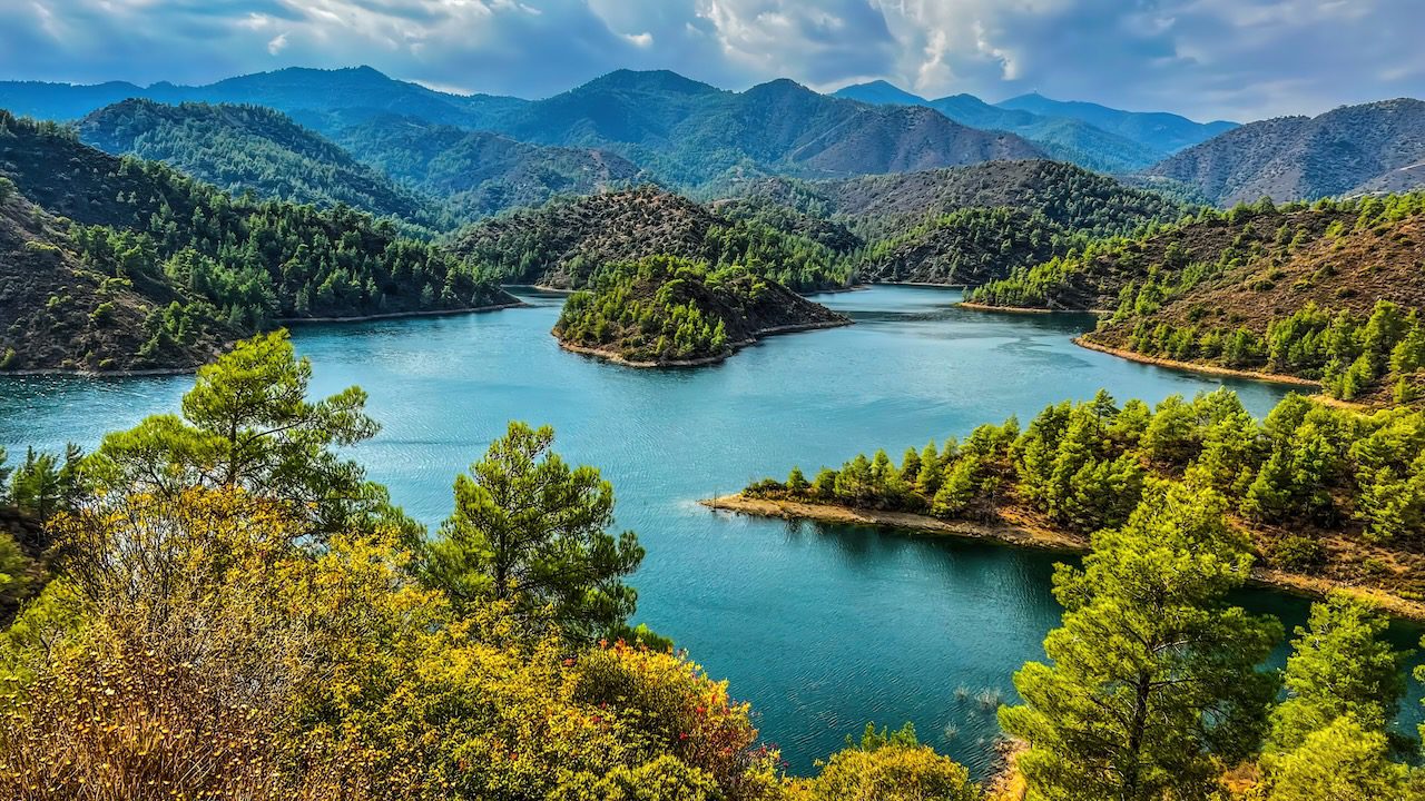 Lefkara Dam in Cyprus, showcasing the tranquil waters surrounded by lush greenery and rolling hills.