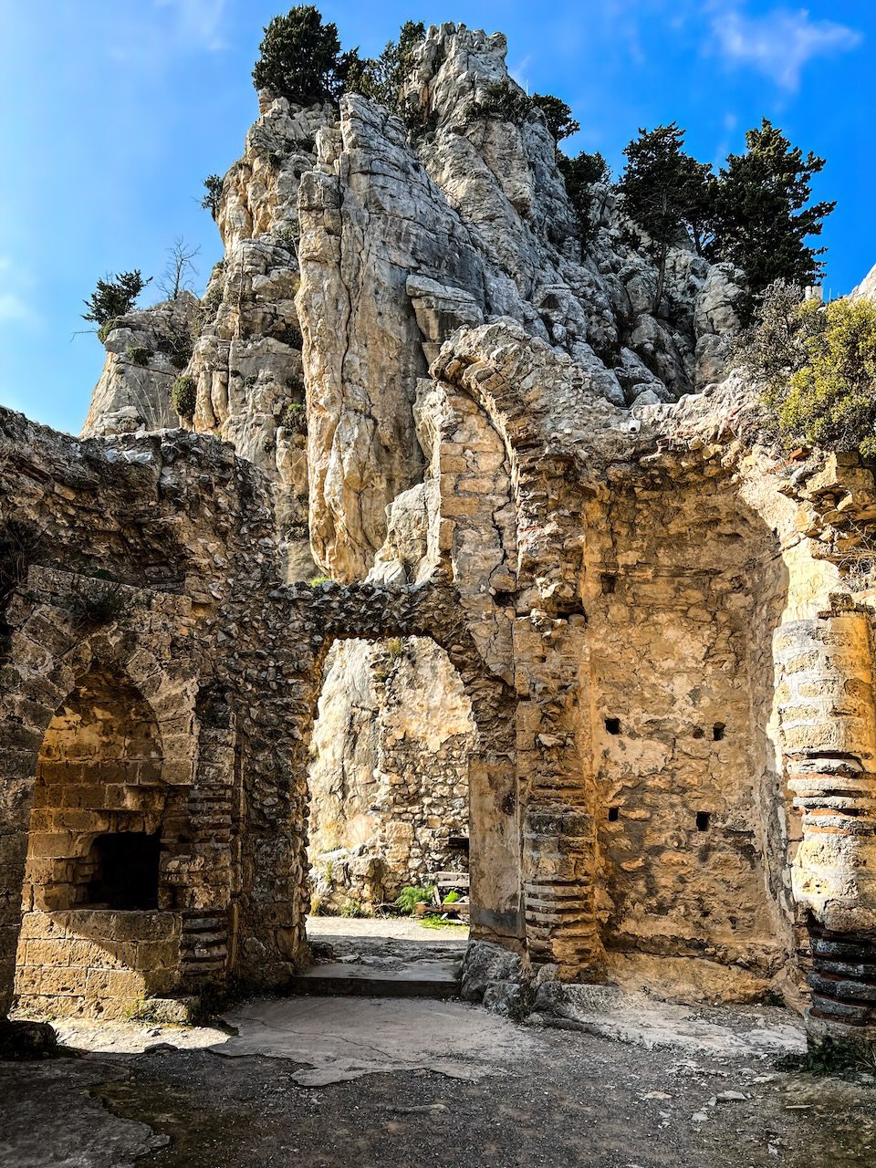 Rugged ruins of St. Hilarion Castle in Cyprus, with arches and remnants of walls set against a dramatic rocky backdrop.