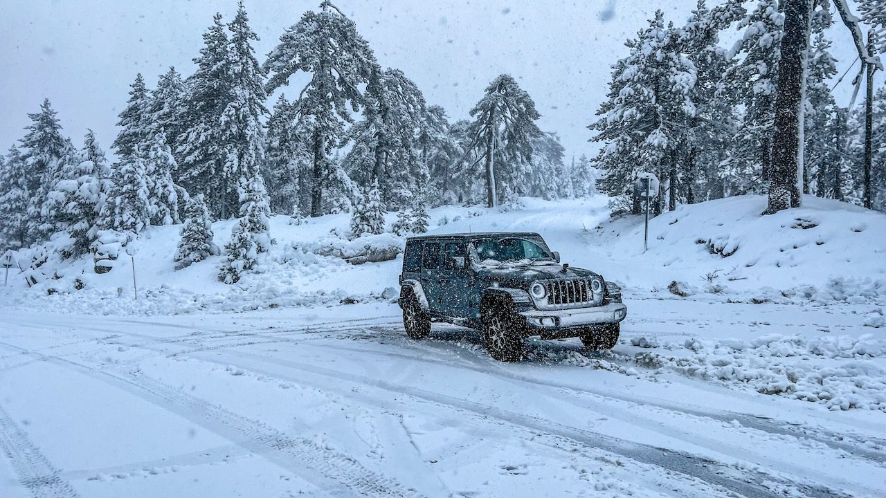 A four-wheel drive braving the snowy roads amidst the Troodos mountains, highlighting a thrilling mountain experience.